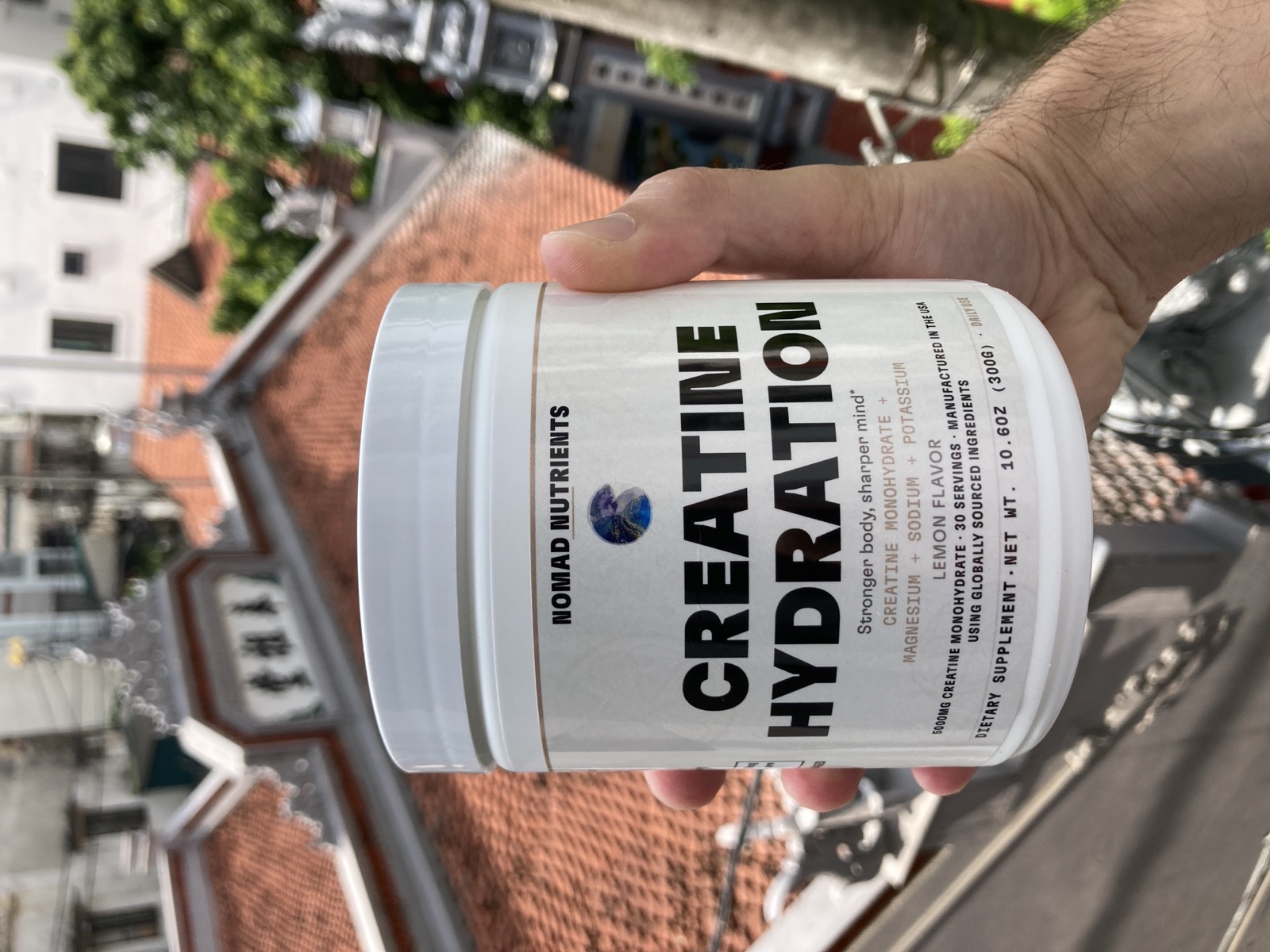 Creatine Hydration Powder (Lemon), held up on a Hanoi rooftop
